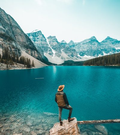 man standing on rock near lake